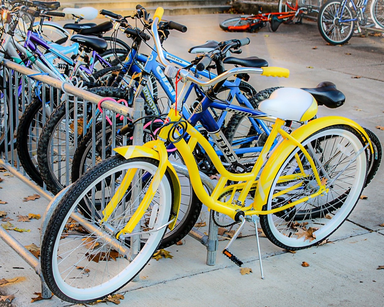 Bright yellow bicycle chained to bike rack with multiple bicycles