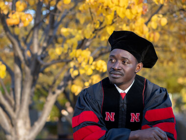 Posed DPH student in plant health regalia in front of an autumn tree